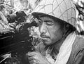 A Japanese soldier aiming at a target through the telescopic sight of his Type 92 heavy machine gun during the Guadalcanal Campaign in 1942.