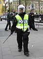 Swedish police in riot gear, carrying an extended telescopic baton