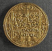 A round gold coin with a square pattern and Arabic calligraphy