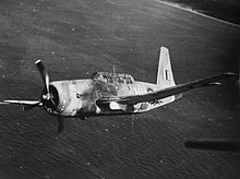 Black and white photo of a single-engined military monoplane flying above a body of water
