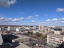 The images shows Saskatoon skyline by day, on a bright clear day, and shows the city rooftops, looking westwards.