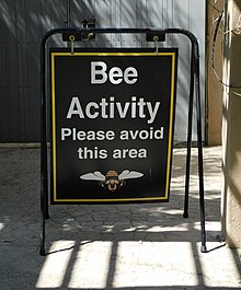 A sign reading "Bee Activity: Please avoid this area"