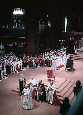 photograph of the interior of Westminster Abbey during the coronation service. The Queen is moving in procession toward the Archbishop of Canterbury