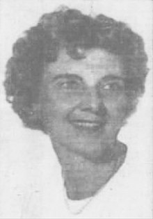 Black and white portrait of a woman with curly, short hair, wearing a bead necklace