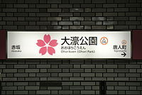Ōhorikōen, Fukuoka: Stationslogo (japanische Kirschblüte), Vollname in Kanji (大濠公園) und Transkriptionen in Hiragana (おおほりこうえん) und Rōmaji, englische Übersetzung und Stationsnummer (K06)