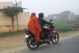 3. Women riding a motorcycle through a village in Western UP as the winter evening fog rolls in.