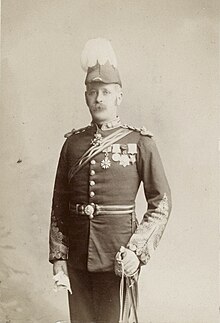 Standing three-quarter length photographic portrait of Charles Moore Watson, in dress uniform with feathered hat, medals and sword