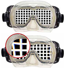 View of a rectangular grating through a flat-glazed diving half-mask, showing magnification and a detail of slight pincushion distortion and chromatic aberration in the through-water view.