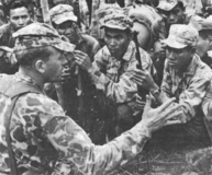 An adviser from United States Army Special Forces briefs members of the Montagnard strike force prior to an operation during the Vietnam War.