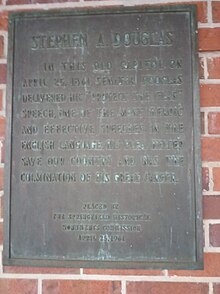 brown plaque on red brick wall reading "In this old capitol on April 25, 1861, Senator Douglas delivered his 'Protect the Flag' speech, one of the most heroic and effective speeches in the English language. His plea helped save our country and was the culmination of his great career."