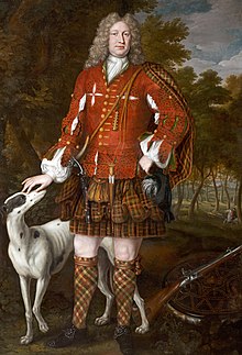 Man approaching middle age, with curly hair or wig, in a red split jerkin over a white shirt and a largely brown belted plaid of complex pattern; he also wears shoes and diced short hose, and is petting a hound, with a musket nearby.