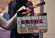 A Denecke clapperboard containing LED display with SMPTE Timecode and colored stripes on the sticks.