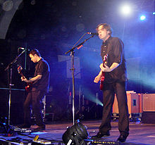 Two men playing guitar on-stage