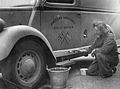 An AAGB member paints a white line around the bottom of her ambulance, in order to make it more visible in the blackout, 1941.