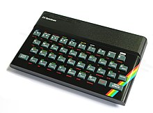 A black, rectangular box with rounded sides. A top panel reads, in raised lettering and a robotic typeface, "sinclair", and below that, in modern, white lettering, "ZX Spectrum". A full QWERTY keyboard with Chiclet buttons, full number set, and buttons for Enter, Caps Shift, and Space. Each of the buttons has alternative text in green and red lettering nearby, to access other functions when the corresponding modifier key is pressed. A red, yellow, green, and blue rainbow streak shows in the right corner, but the rest of the machine is black.
