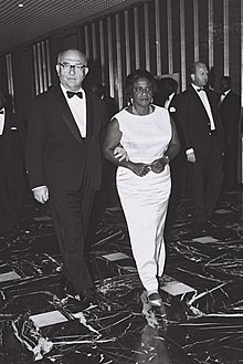 Liberian First Lady being led into dinner by Israeli politician, both wearing evening dress.