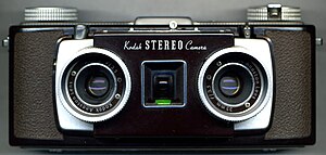 A Kodak Stereo Camera. Brown in color, it features two lenses, one next to the other, with a viewfinder between the two.