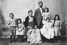 Photograph of Pontic Greek man, woman, and their children. The man is dressed in Western clothes, the woman in traditional costume.