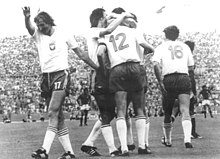 Football players in white shirts and dark shorts celebrating together