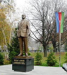 Statue of Aliyev in a park with cyrillic script on plinth below