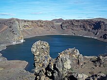 A blue lake within a crater-like depression in the landscape