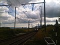 Masts in place for the future 25 kV overhead wires at Bourdigny looking toward Satigny. A Geneva bound FLIRT has just left Satigny