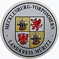 Zulassungsplakette des Landkreises Müritz mit dem mecklenburg-vor­pommerschen Lan­deswappen bis 2011