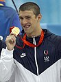 title=Michael Phelps holding up a gold medal