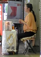 A Japanese palm-reader waits along the street for a customer, 2015