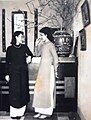 Two women in áo dài chatting.