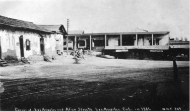 Looking east on Arcadia towards houses lining the east side of Broad Place. Aliso Street runs form their right side towards the background. Calle de los Negros runs to the left in front of them. The Coronel Adobe is at left.
