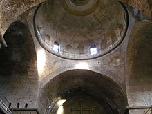 Bare interior of the former church of Hagia Irene in Istanbul showing the convergence of four short barrel vaults at the pendentives, windowed drum, and main dome