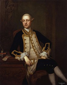 Portrait of Maurice Suckling in blue naval uniform sitting in a chair with his legs crossed
