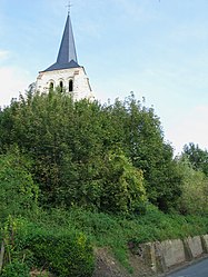 The stone bell tower, of a brilliant white due to a recent restoration, emerges from the wooded hill overlooking a part of the village.