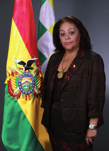 Official portrait of Betty Tejada flanked to the left by the Bolivian tricolor and the Wiphala.