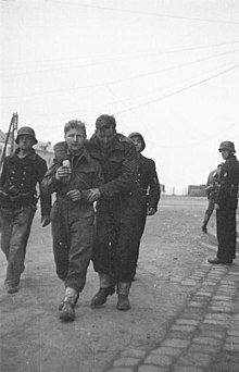 two British soldiers one wounded being escorted by three armed Germans