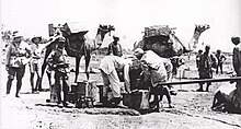 Three soldiers look on while Egyptian workers fill a water fantasie from a pipe