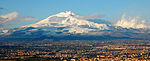 Mt Etna, covered with snow, with a city in front