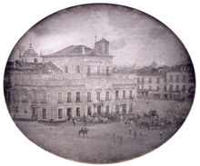 Photograph showing the Imperial Palace in Rio de Janeiro with carriages and mounted honor guard in the square fronting the palace.
