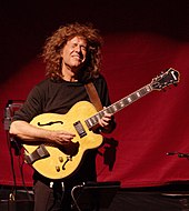 A man with his eyes closed playing a guitar.