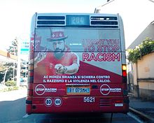 A picture public bus from behind, with a picture of a man wearing a red shirt and hat posing for an advertisement against racism