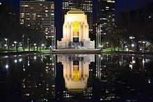 Photograph of a large memorial building at night. The building is being reflected in a body of water in front of it.