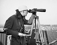 An ornithologist uses a spotting scope at Rossitten Bird Observatory in 1939. This spotting scope has no zoom eyepiece, but three interchangeable eyepieces with different magnifications