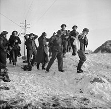 four Germans one with a white flag surrounded by British troops crossing a snow-covered landscape