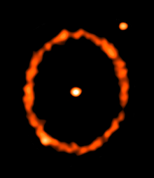 The star is seen at the centre and the ring shows the main belt of the debris disc, which is located at 70 astronomical units from the star. The belt appears elliptical as it is slightly inclined from face-on. In addition to the star, two other point sources appear in the image (one coincident with the belt). These are background galaxies and not part of the epsilon Eridani system.