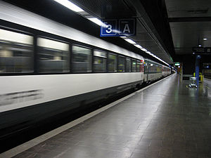 White train leaving underground side platform