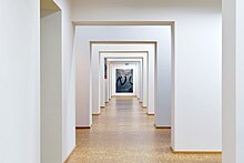 Blick in den Gang des Kunstvereins Offenburg, von dem links und rechts die einzelnen Räume abgehen. An der Wand geradeaus befindet sich ein abstraktes Gemälde