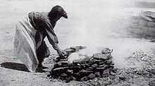 black-and-white photograph of a woman leaning over a fire