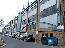 An external view of a sports stadium, with a large amount of blue detail on the facade.
