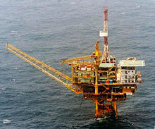 A yellow oil rig in the ocean pointing left
